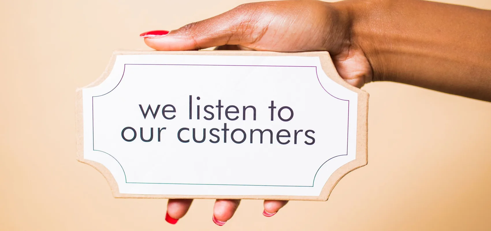 Pancarte « we listen to our customers » tenue à la main, symbole de l’écoute client