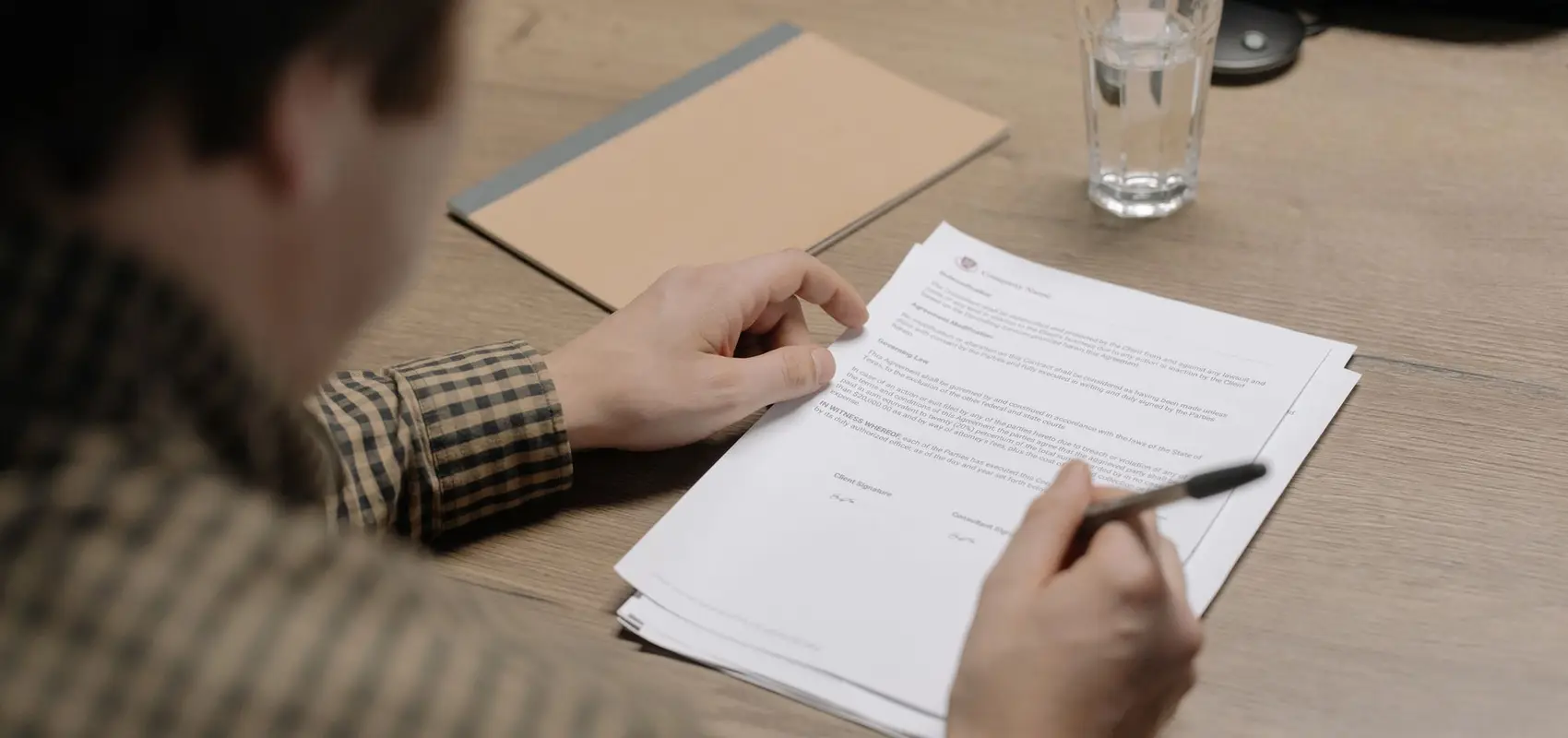 Dirigeant relisant un contrat posé sur une table de réunion, stylo à la main
