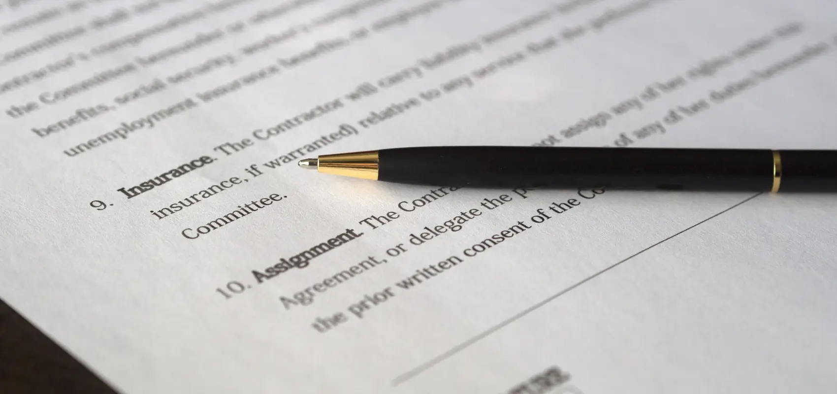 Stylo posé sur les clauses imprimées d’un contrat, à côté de la ligne de signature