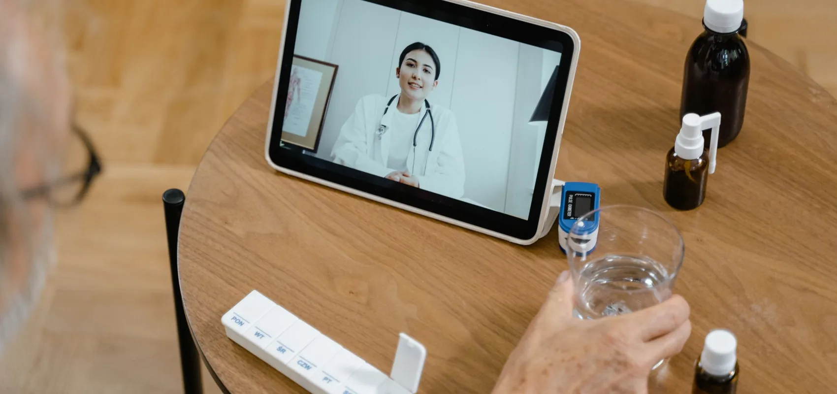 Téléconsultation médicale affichée sur une tablette posée sur une table, à côté de médicaments