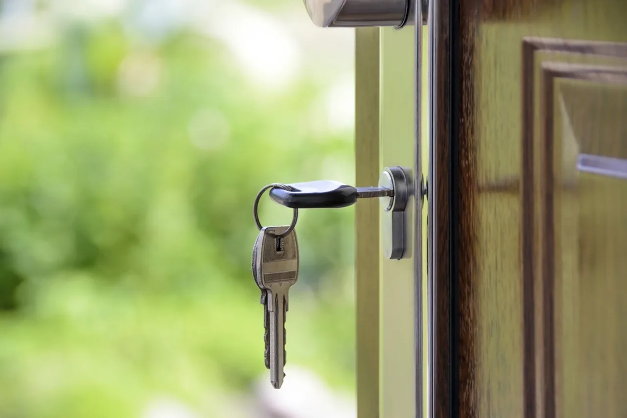Trousseau de clés inséré dans la serrure d’une porte ouverte sur un jardin