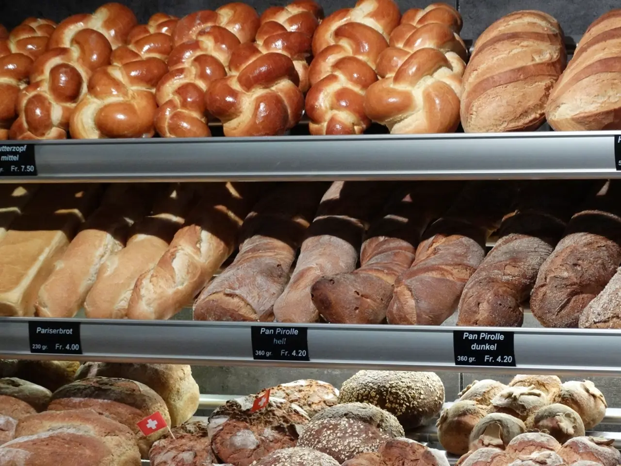 Pains et viennoiseries alignés sur les clayettes d’une boulangerie