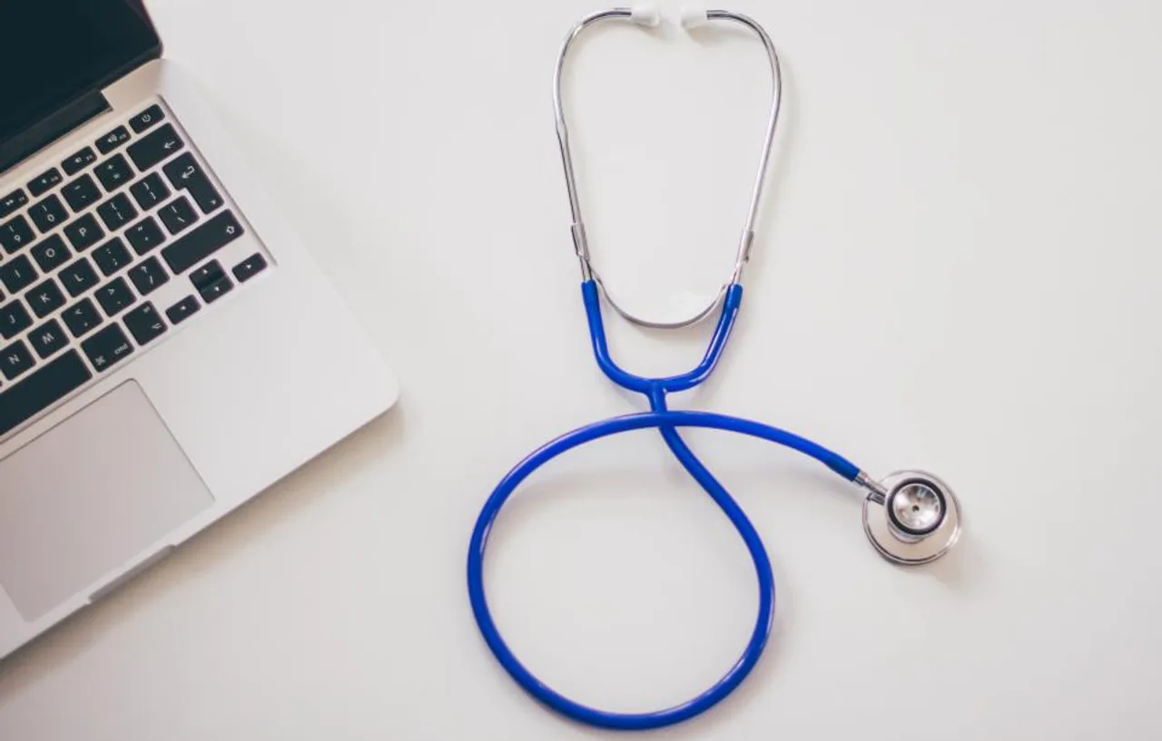 Stéthoscope posé à côté d’un ordinateur portable sur un bureau blanc