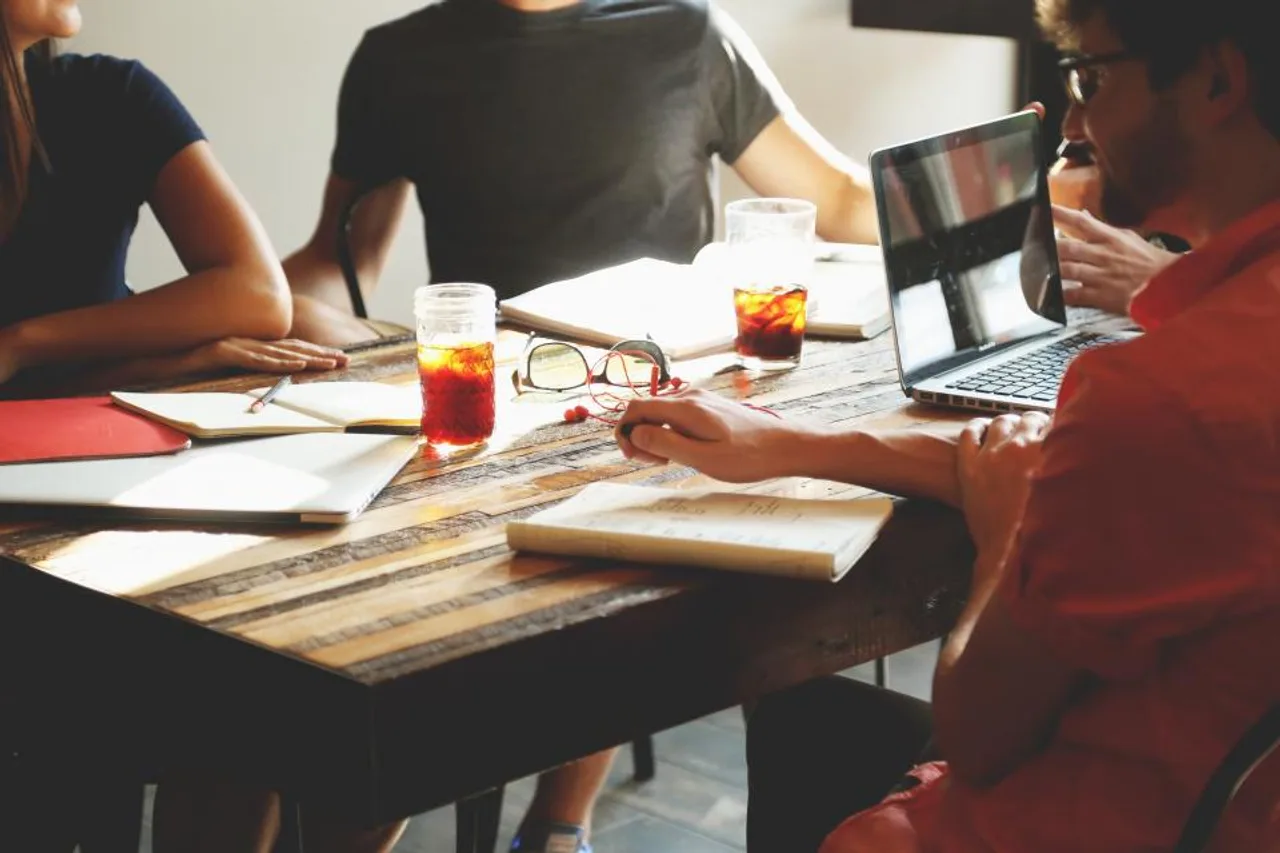 Équipe réunie autour d’une table de travail avec ordinateur portable et carnets pendant une session de cadrage produit