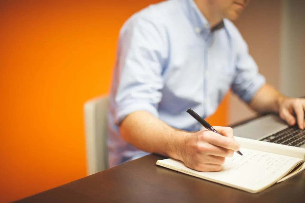 Dirigeant prenant des notes devant son ordinateur portable dans un bureau lumineux