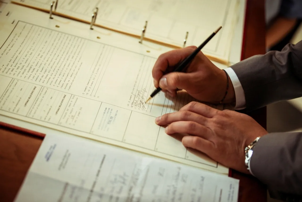 Mains signant un contrat posé sur un bureau, stylo à la main