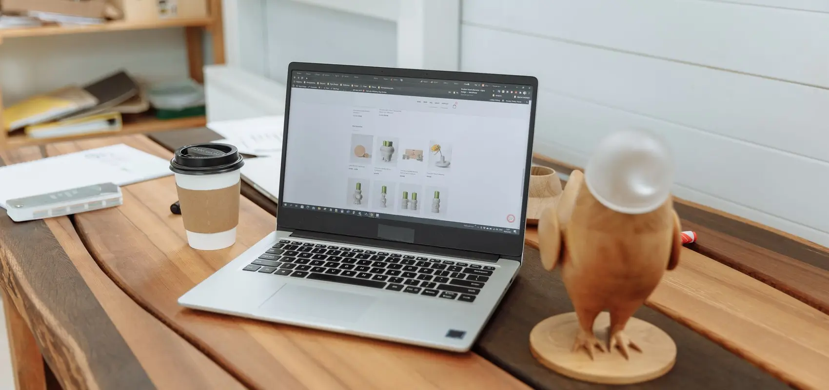 Ordinateur portable ouvert sur un site web, posé sur la table en bois d’un petit bureau