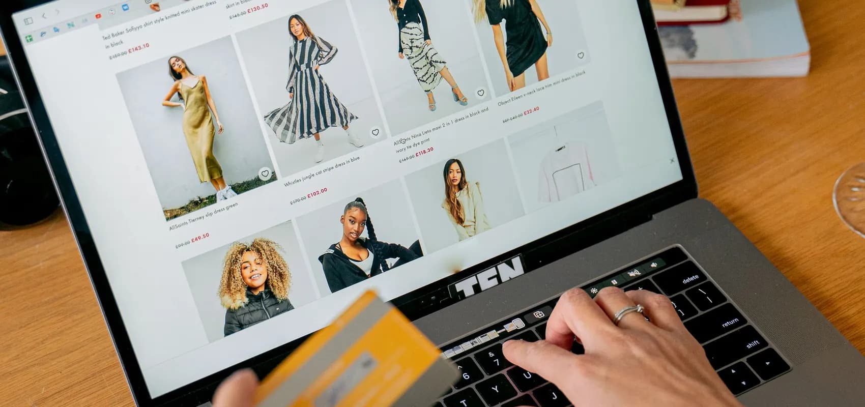 Achat en ligne sur une boutique de mode depuis un ordinateur portable, carte bancaire en main