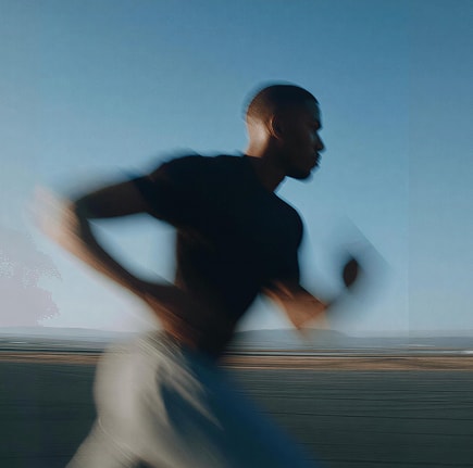 Un coureur en plein effort, silhouette floutée par le mouvement au bord de mer